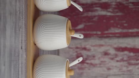 three white ceramic spice jars on a wooden rack