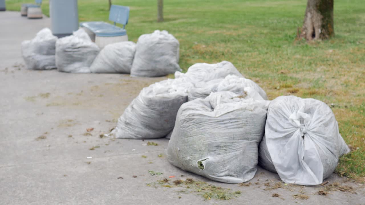 야드 폐기물 으로 가득 찬 쓰레기 가방 의 줄 이 공원 의 보행자 길 에 앉아 있다