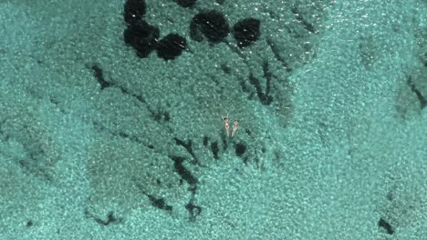 Bird’s-eye-view-of-two-female-friends-floating-in-crystal-clear-water-during-summer-vacation-near-Sardinia-island,Italy