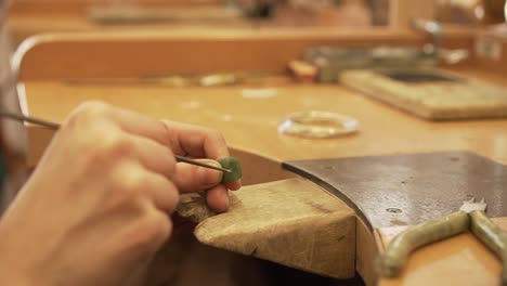 detalle de llenar un pequeño agujero en piedra verde de nueva zelanda en fábrica de joyería - cámara lenta