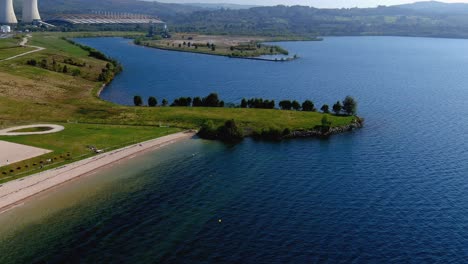 gente disfrutando de la planta de energía térmica de la playa del lago con jardines y agua limpia en una tarde soleada