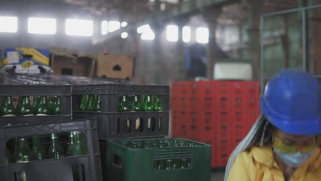 woman in mask working at the recycle waste separation of recyclable waste plants. sorting and arranging glass bottles into boxes for further disposal. slow motion