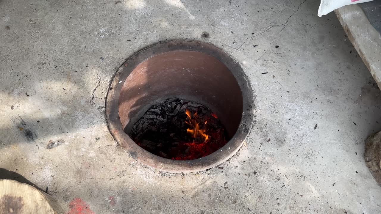 Eastern Japanese hot tube cylinder wood fire oven made by clay and goat hair hot wood stick fire to make traditional flat fresh crunchy bread in a Persian lifestyle in middle east woman life freedom