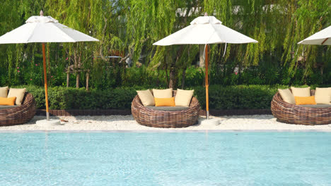 umbrella-with-bed-pool-around-swimming-pool-with-ocean-sea-background---holiday-and-vacation-concept