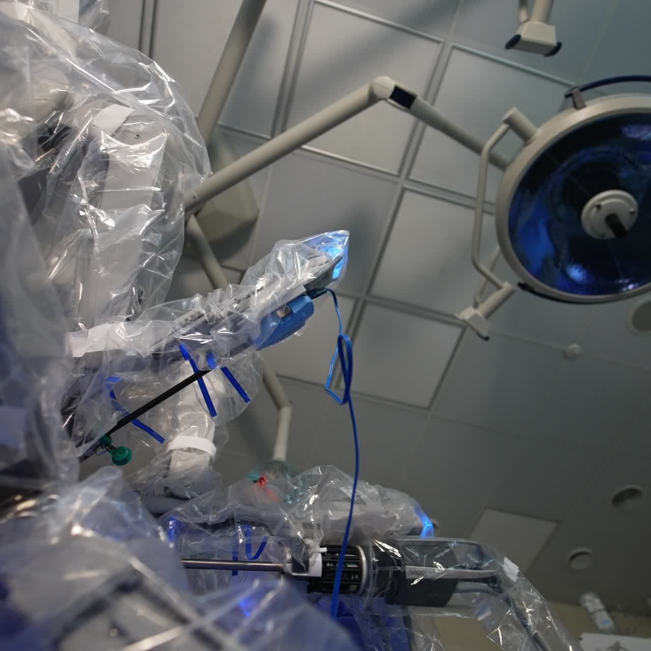 Futuristic robot surgeon working at operation in surgery room. First assistant is in the operational field. Low angle view