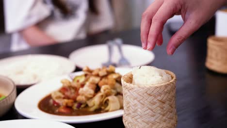hand serving sticky rice from woven container