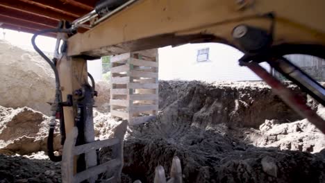 zoom-out shot revealing steel bucket of an excavator at the construction site - construction equipment