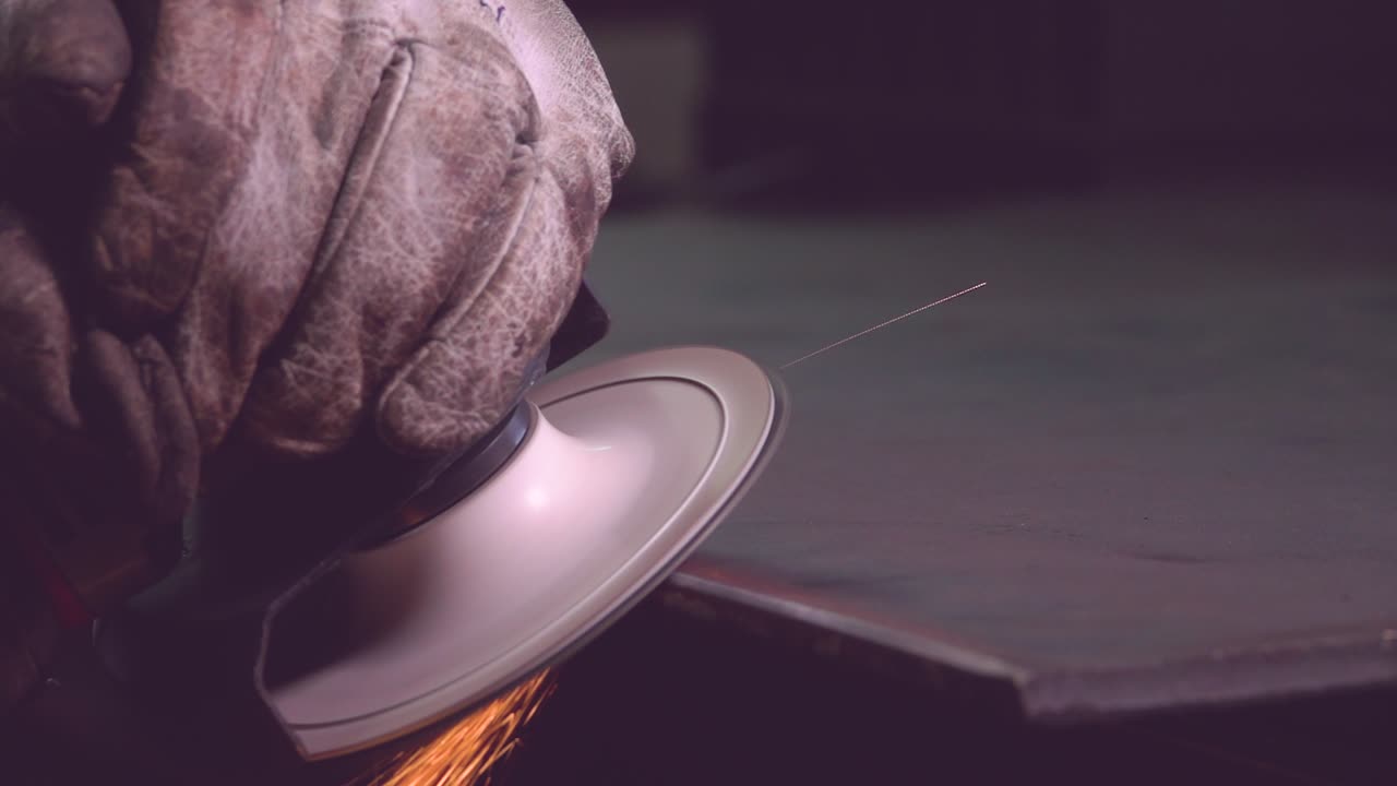 trabajador de metal de cosecha en guantes moliendo el borde del trabajo manual de metal