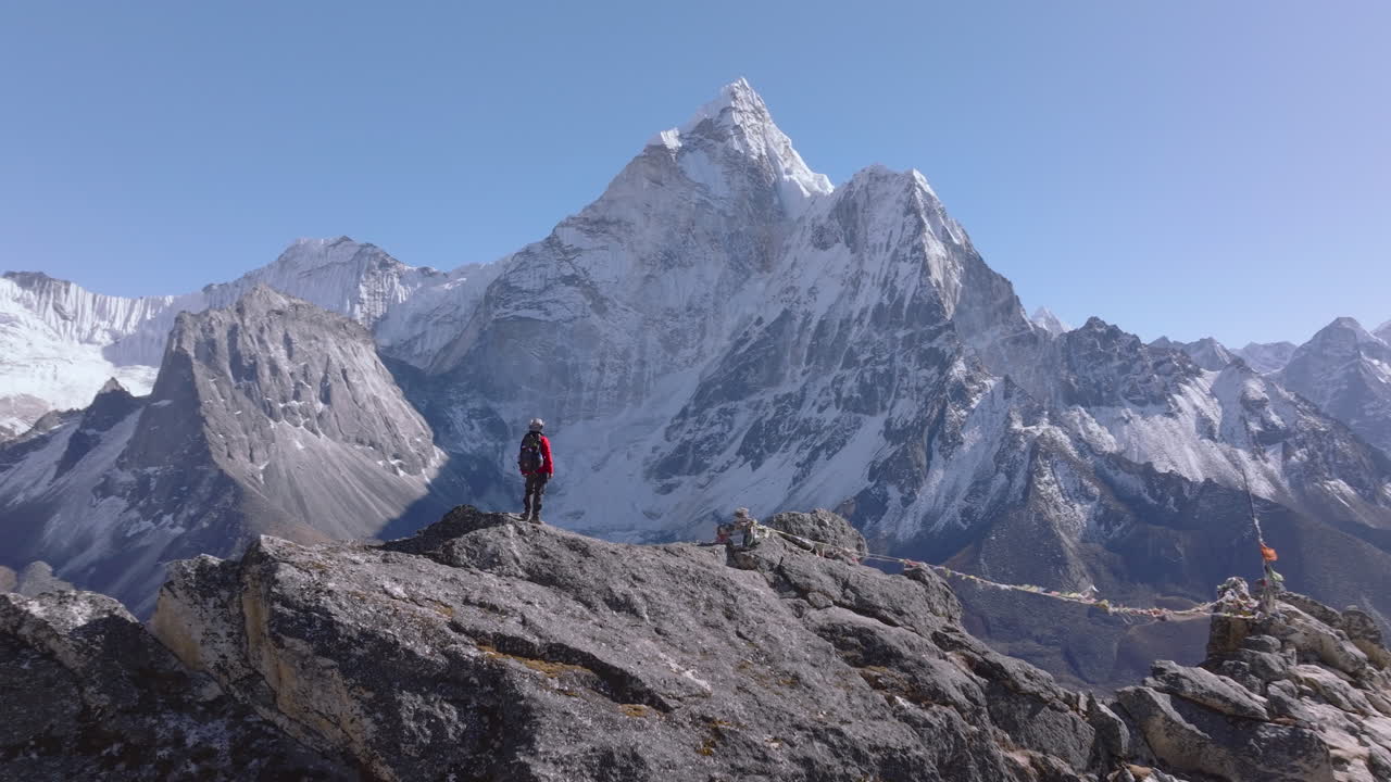 Un turista ammira la vista panoramica himalayana dal Picco di Nangkartshang, vicino a Dingboche, che rivela l'Ama Dablam e la catena montuosa circostante nella regione dell'Everest, in Nepal.