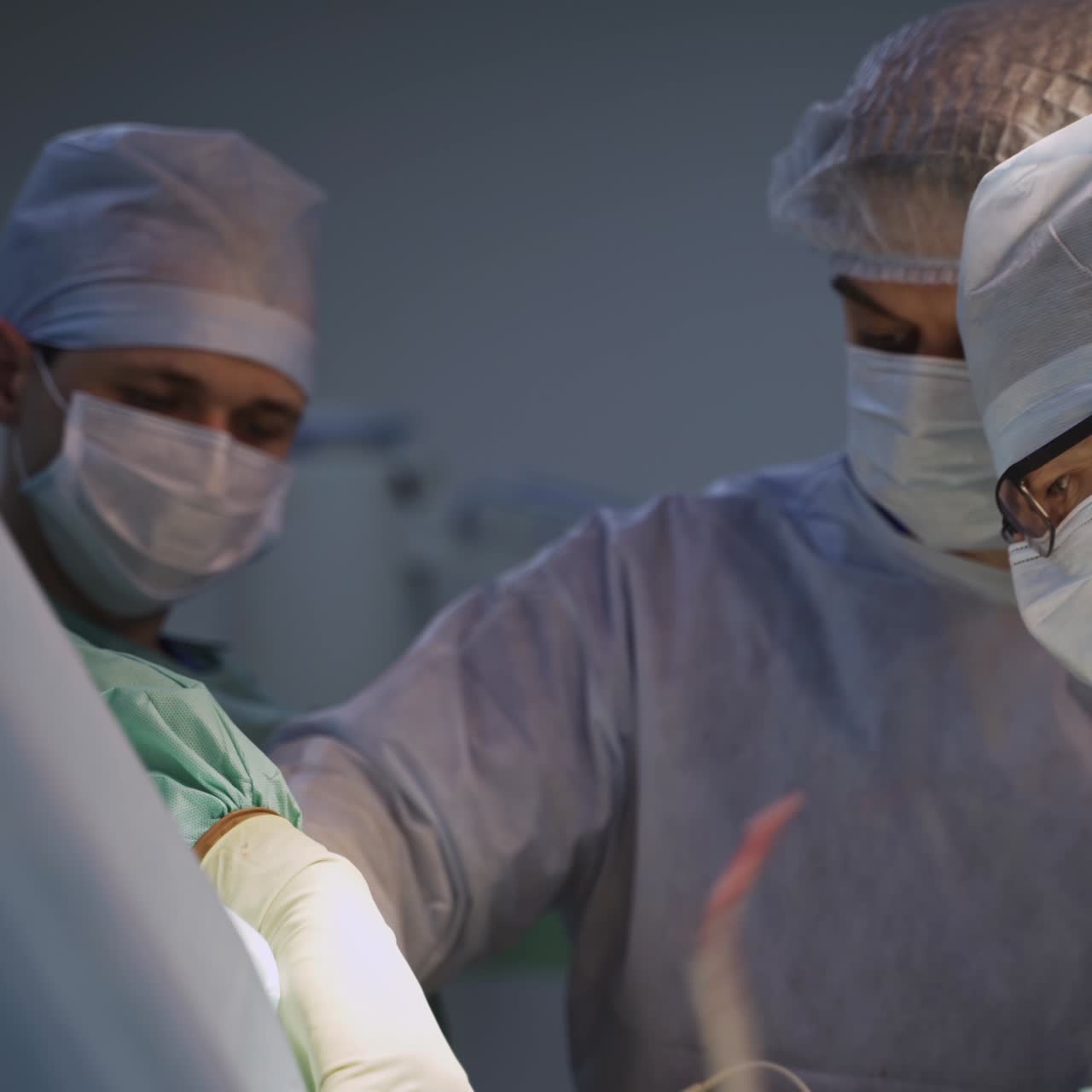 Samarbejdende gruppe bestående af tre mandlige kirurger under operation. Teamwork under operationen af patienten i en moderne operationsstue.