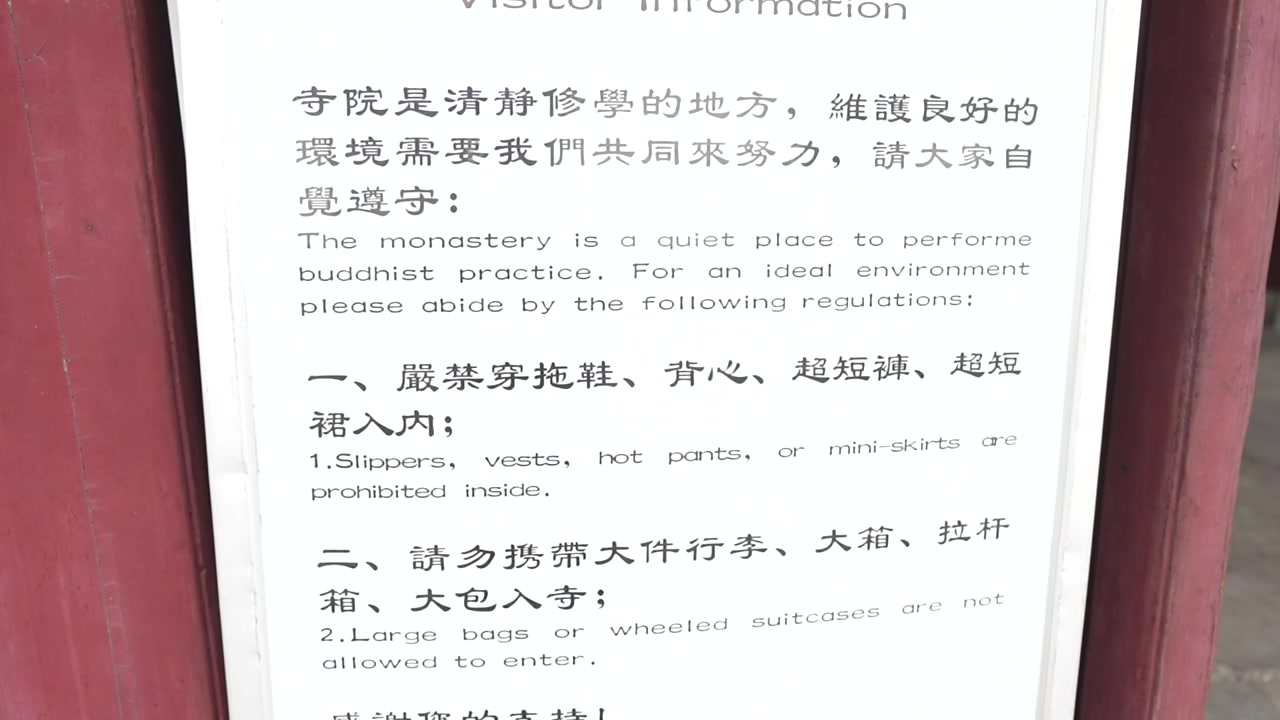 Close up of a bilingual visitor information sign with regulations for entering a Buddhist temple