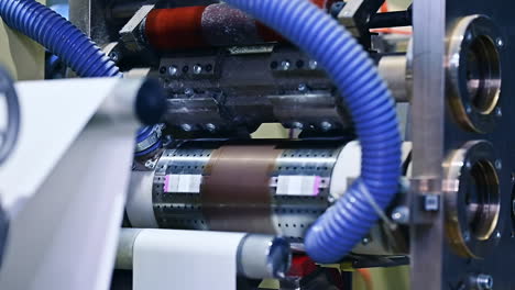enterprise for the production of diapers. spinning shafts rotate and move the white layer between the gears of machine. mechanism at work close up.