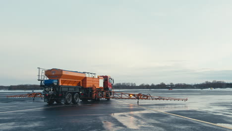 winter snow and ice removal truck with chemical spraying equipment working on airport taxiway