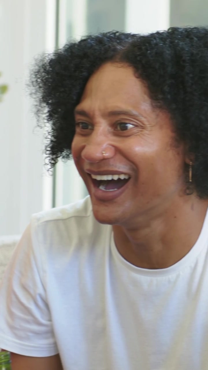 African American friends on couch red jersey man turning after friends joking with glasses smiling