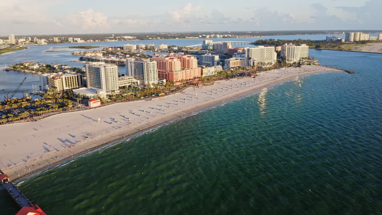 The long pier of Clearwater Beach extends into the Gulf of Mexico, framed by turquoise waters and a row of modern resorts overlooking the white sandy shoreline