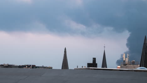 Pan-over-roofs-as-smoke-rolls-over-roofs-in-Antwerp,-Belgium