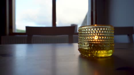 golden candle holder on table with soft focus, warm indoor mood, dusk light from window