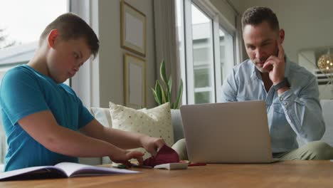 Kaukasischer-Vater-Mit-Sohn,-Der-Am-Tisch-Sitzt-Und-Zu-Hause-Mit-Dem-Laptop-Lernt