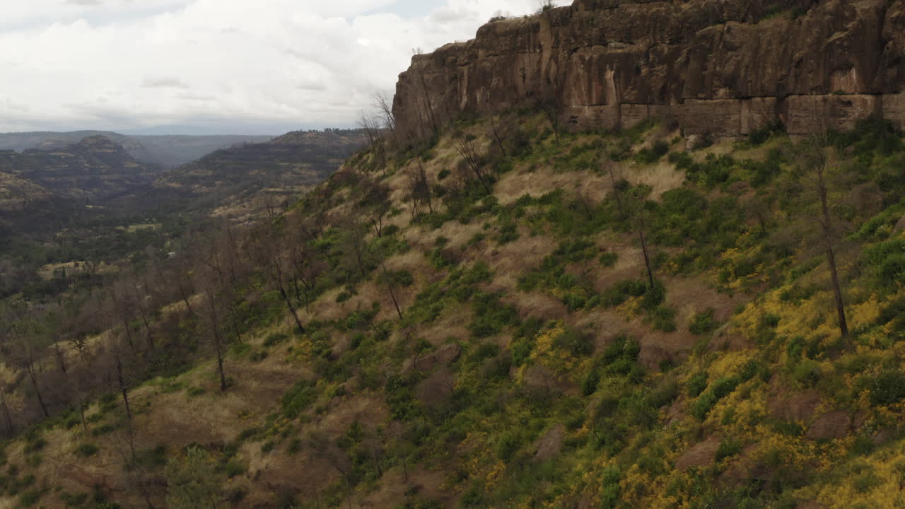 Aerial: flight along butte hilltop over canyon valley, remote countryside