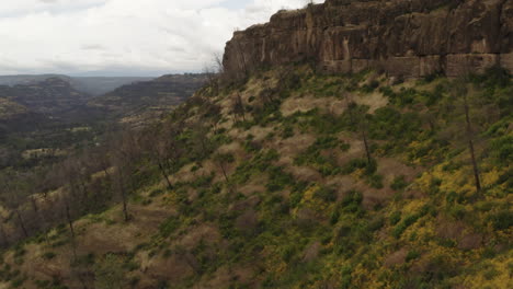 aerial: flight along butte hilltop over canyon valley, remote countryside