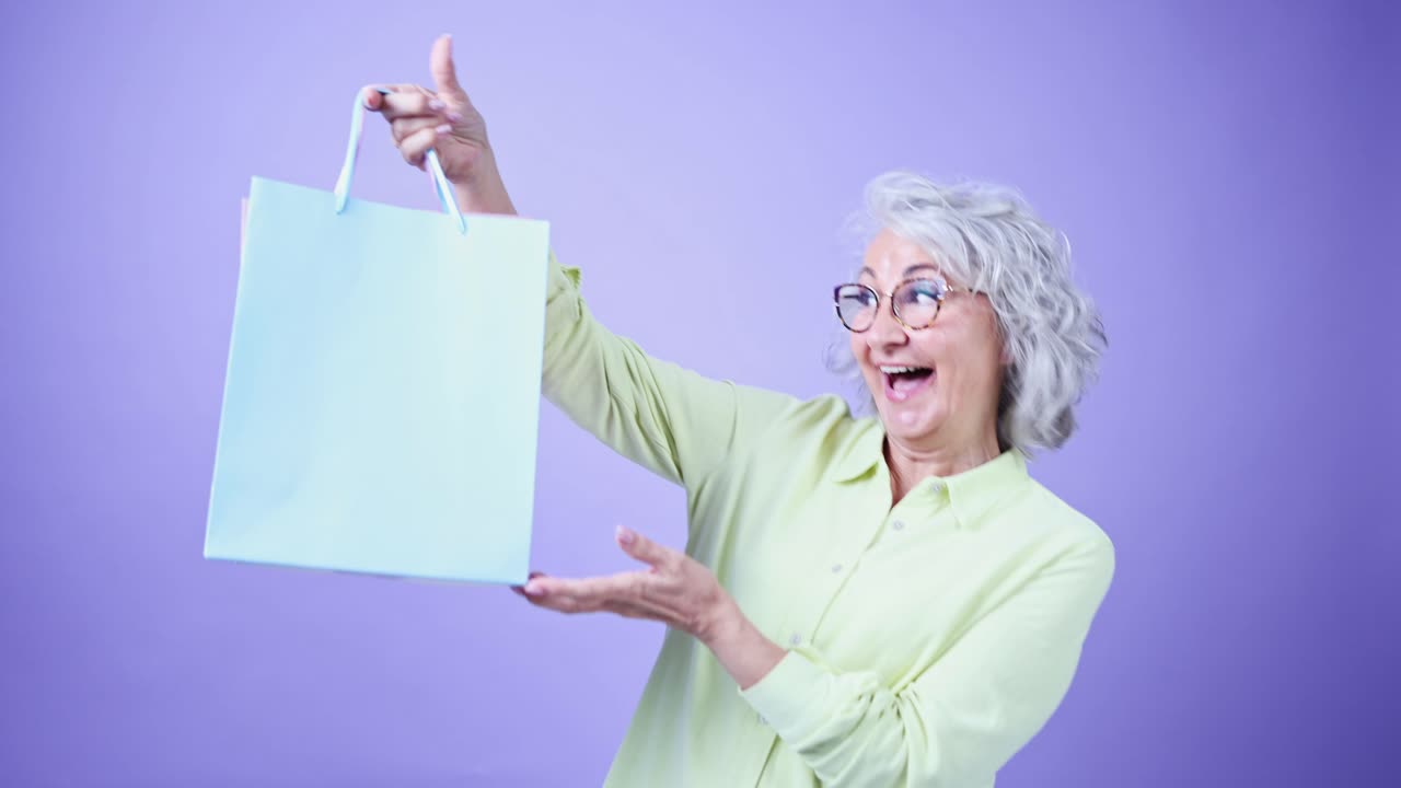 Mujer mayor feliz riendo y mostrando una bolsa de compras