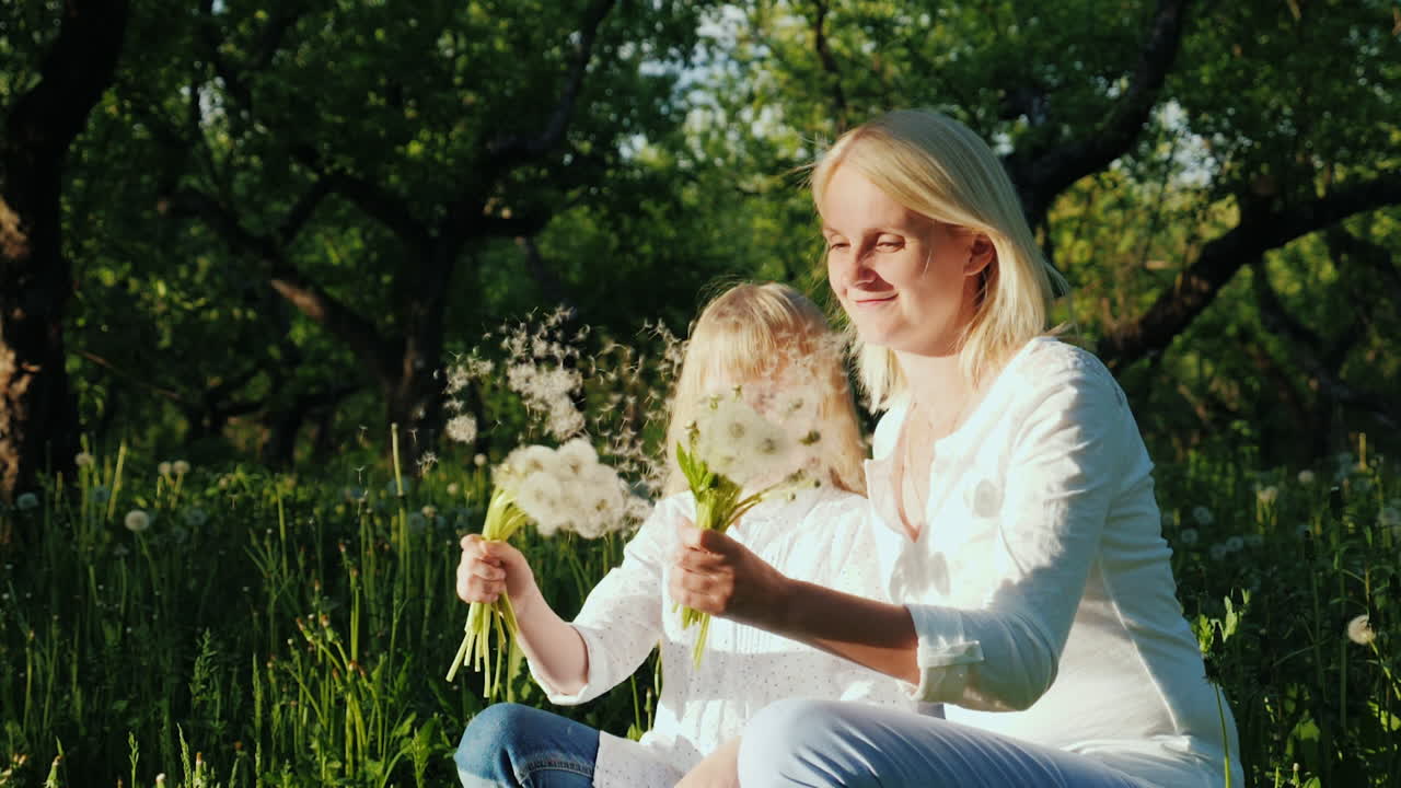 mamá e hija están jugando con dientes de león para pasar un buen rato juntos video en cámara lenta