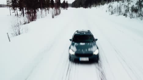 Ein-Elektroauto-Fährt-Unter-Einer-Drohne-Auf-Einer-Verschneiten-Straße-Am-Polarkreis-Vorbei