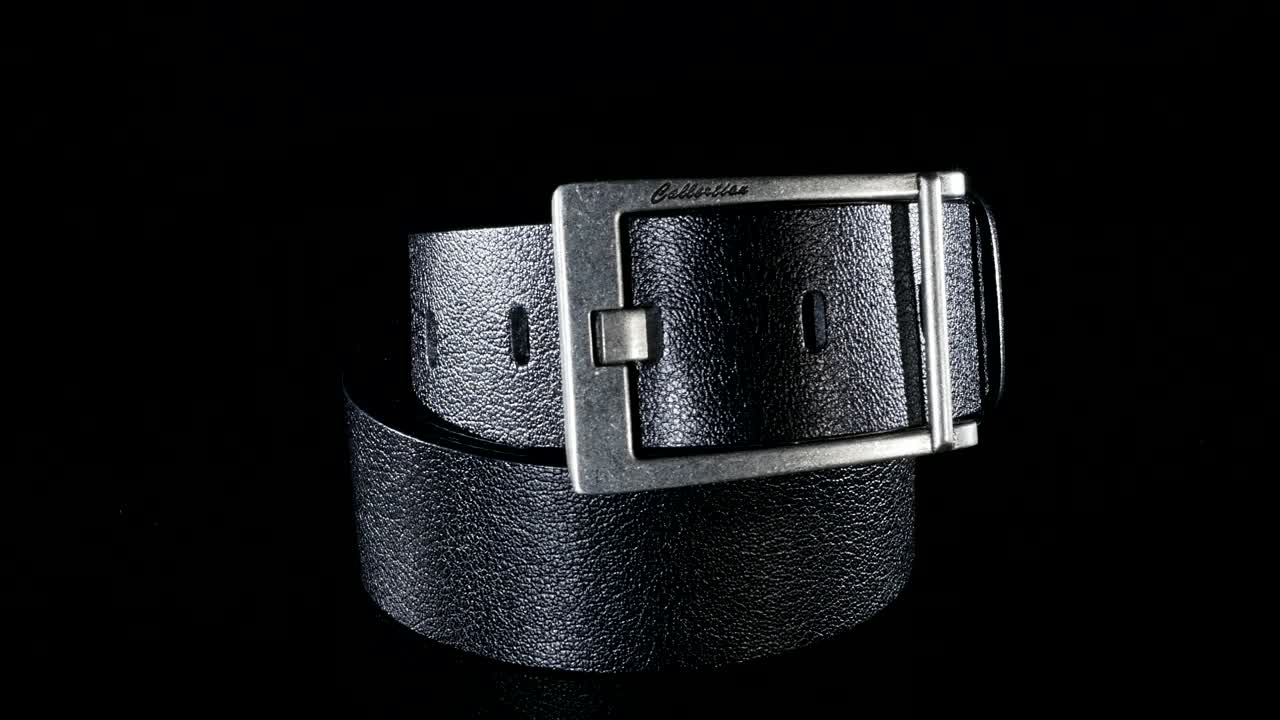 검은색 남성의 벨트는 검은색 배경에 회전합니다.