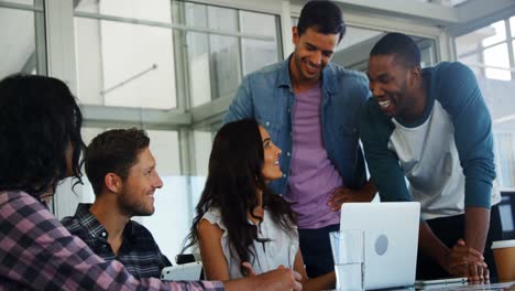 Happy-executives-discussing-over-laptop