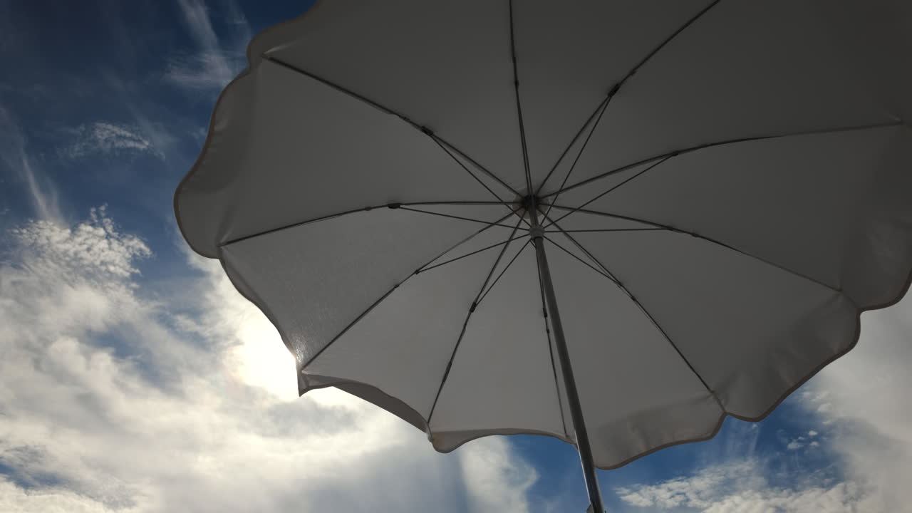 Sunny seaside view with white beach umbrellas framing a bright blue sky and calm sea