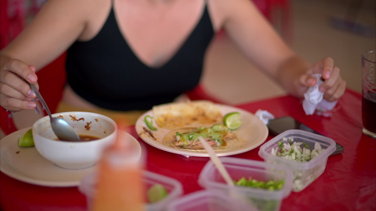 cierre en cámara lenta de una mujer latina preparando su taco de barbacoa con una cucharada de caldo en un restaurante en méxico