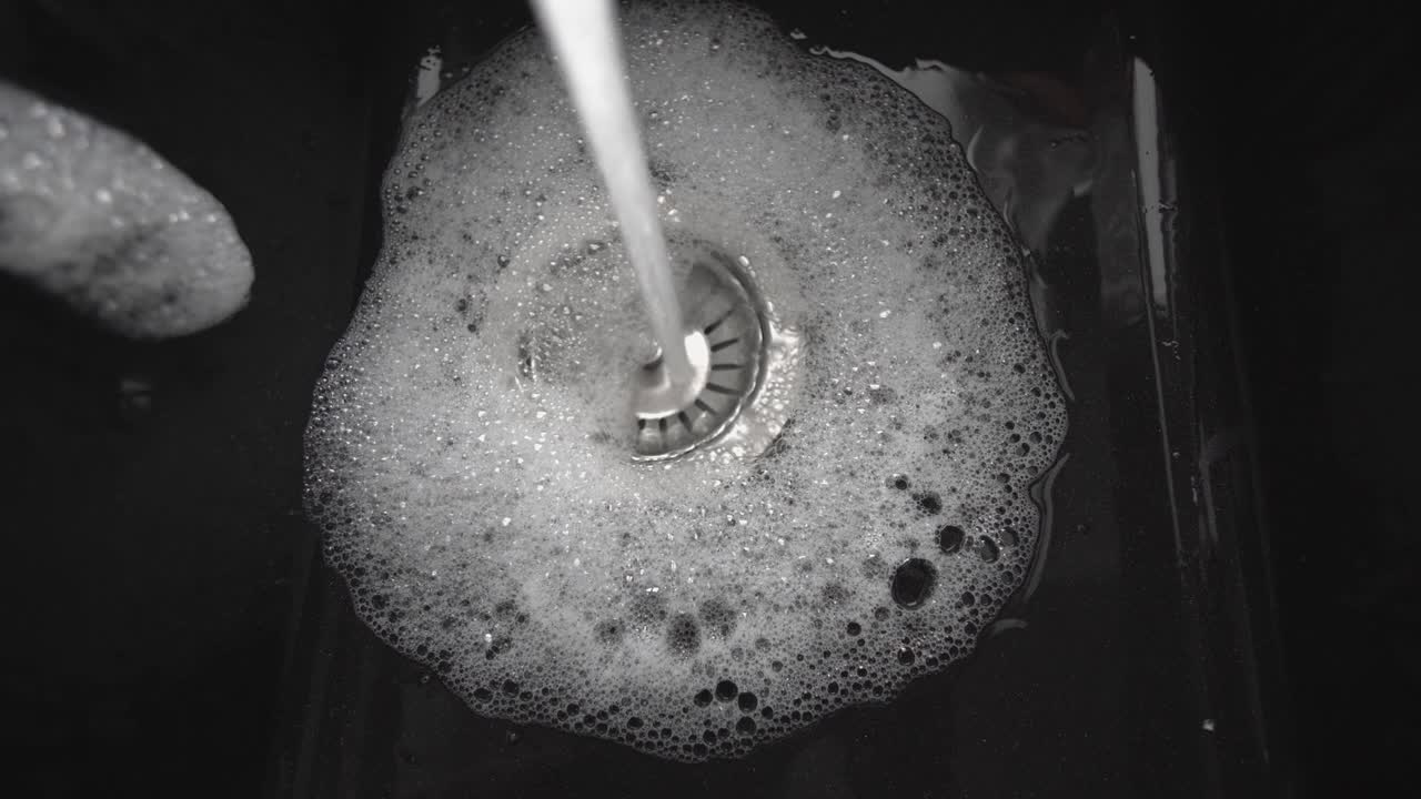 개방된 프에서 검은색 그라나이트 싱크대로 물이 흐르고 있습니다.