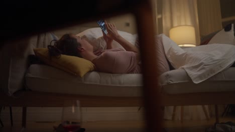 woman using phone on sofa at night