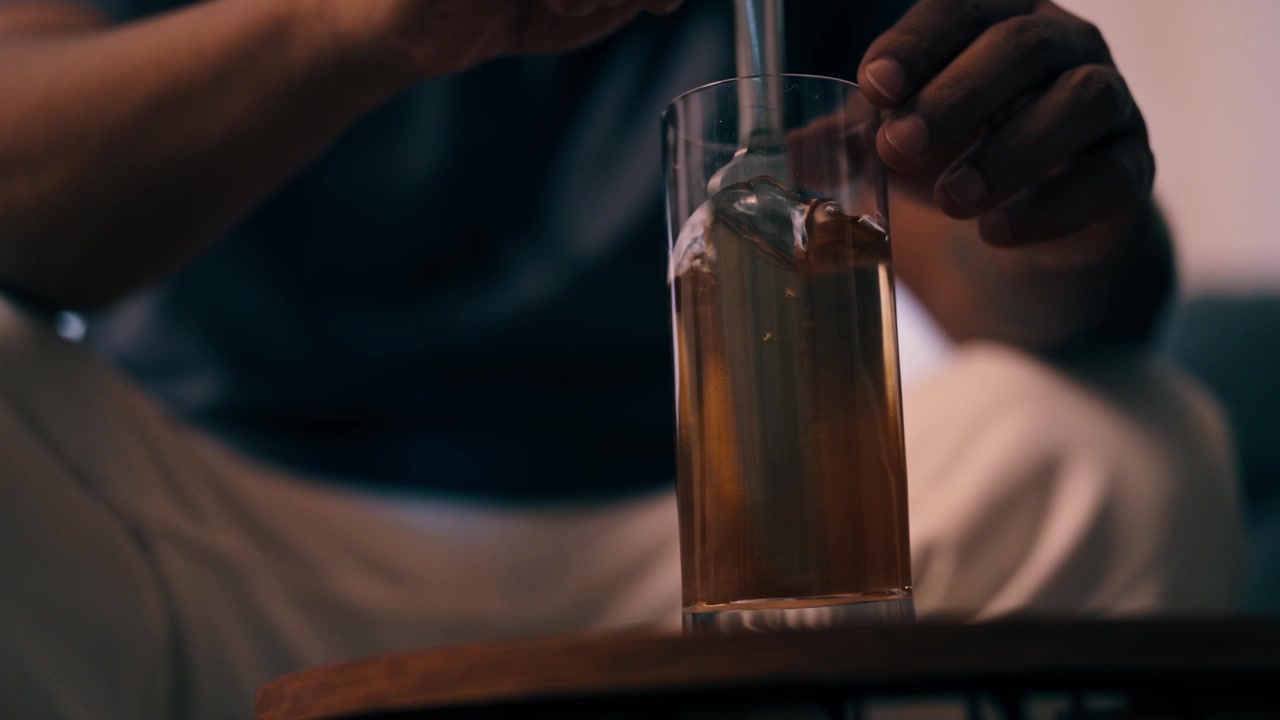 Una mano usa un cucchiaio per mescolare un farmaco disciolto in un bicchiere d'acqua a casa.