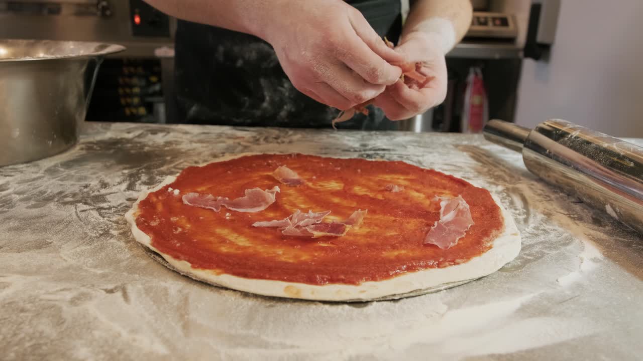 Lo chef prepara la pizza. Pizza con salsa e prosciutto crudo