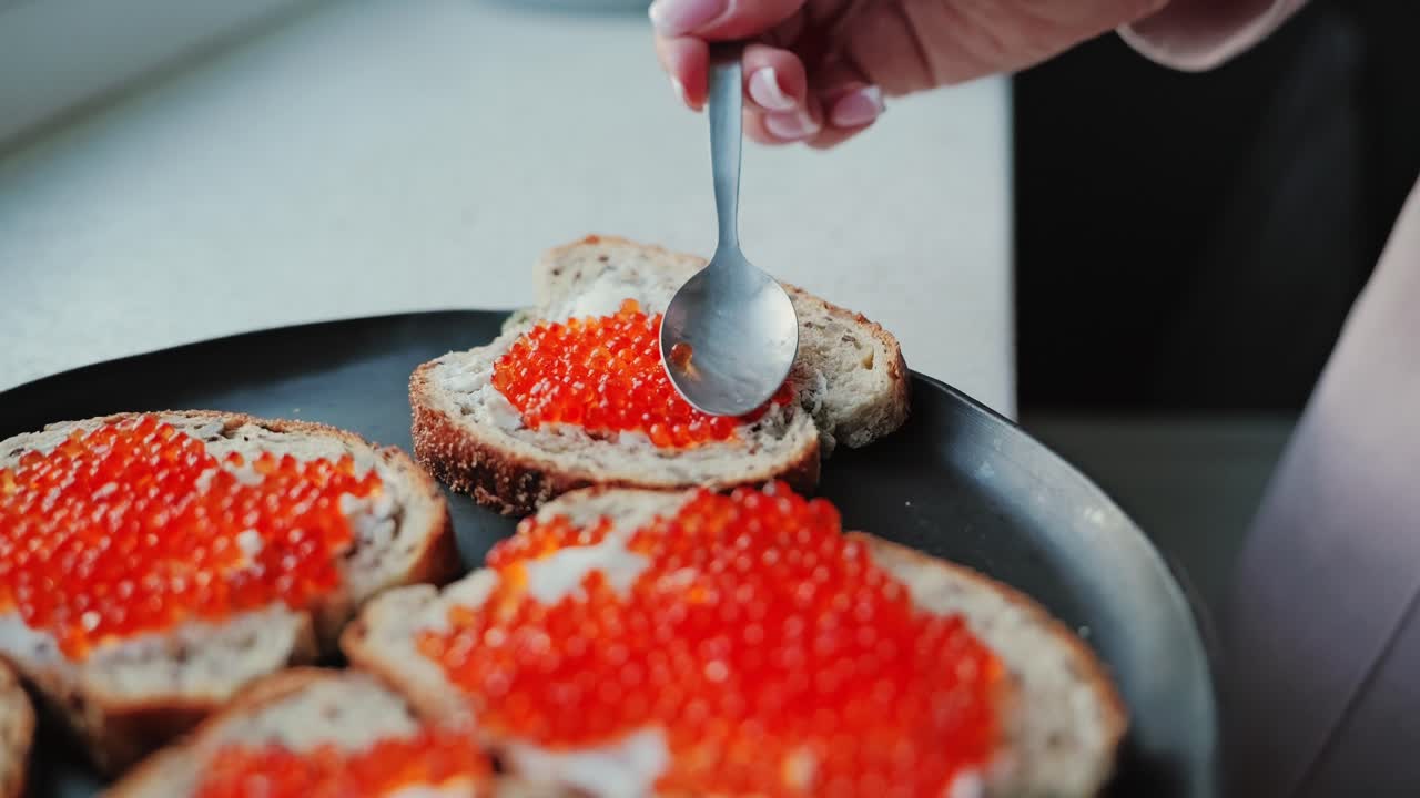 Delicate close up slow motion of red caviar being spread on rustic bread