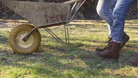 vista en primer plano de una pareja caucásica caminando por el campo mientras llevan una carretilla