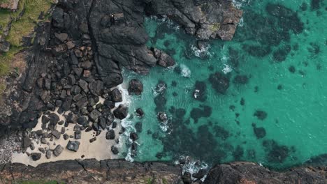 high birdseye view of secluded beach cove framed by dramatic cornish rock formations