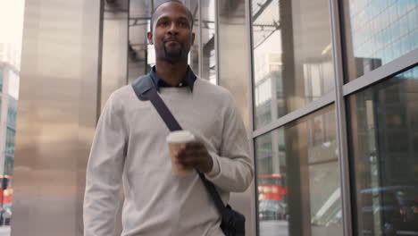 african american businessman walking through city using smart phone