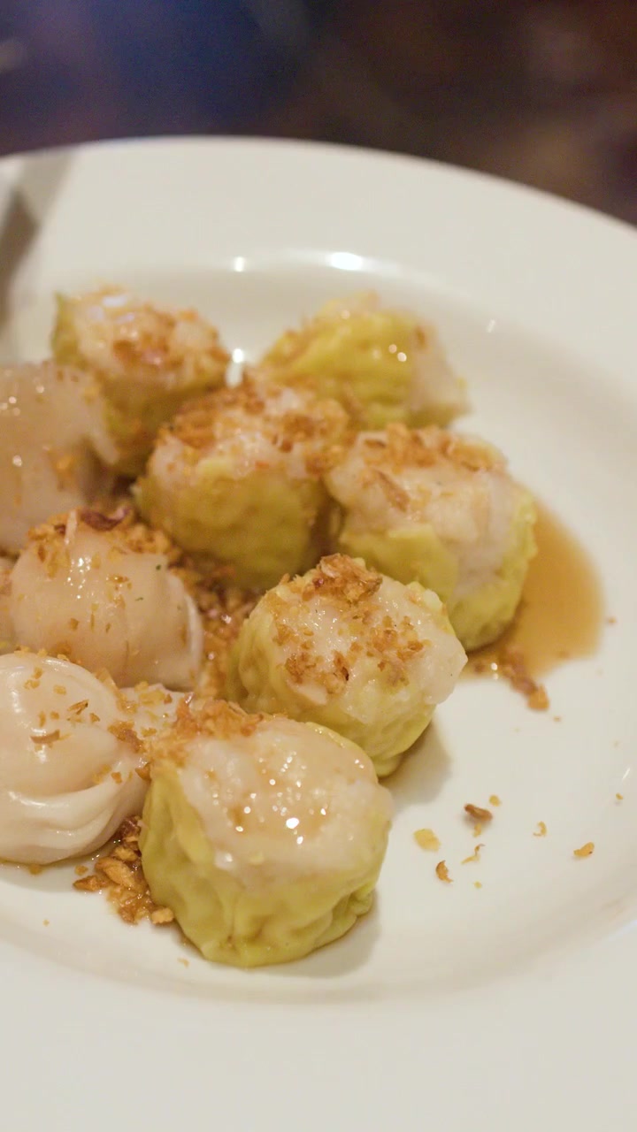 Primo piano di un cucchiaio che sparge aglio fritto su gnocchi shumai di gamberi e maiale