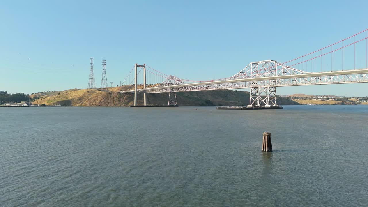 Footage captures the Alfred Zampa Memorial Bridge spanning across the Carquinez Strait, as seen from the Crockett shoreline under warm California skies