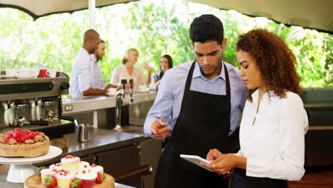 Male-and-female-waiter-discussing-over-digital-tablet