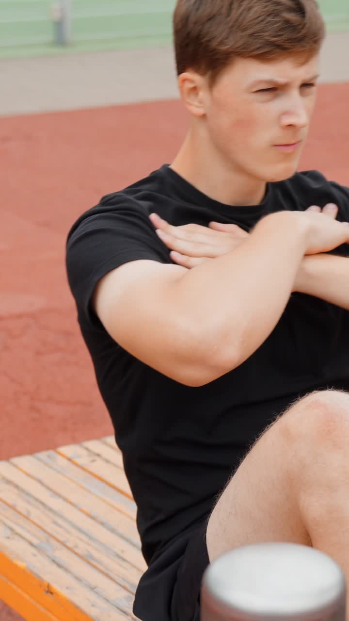 Young Man Doing Cross Arm Crunches Exercise. - vertical shot