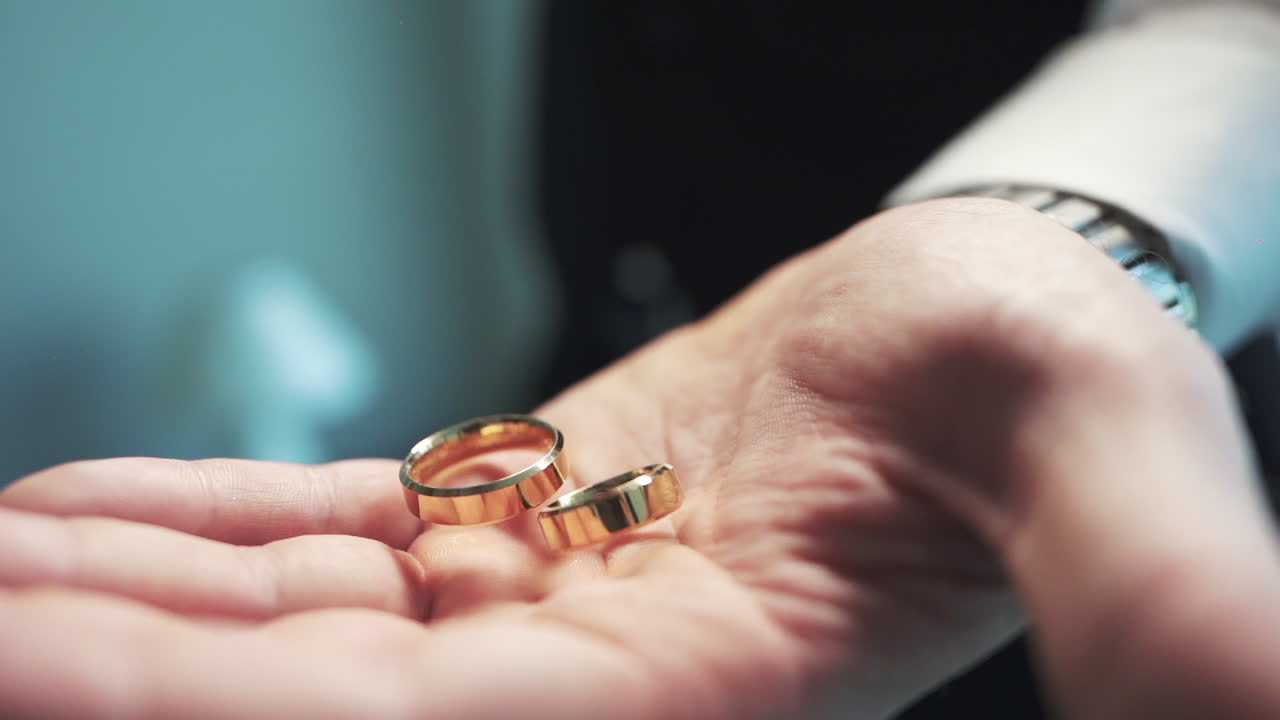 Groom holds golden rings before ceremony, elegance and promise in bridal preparation