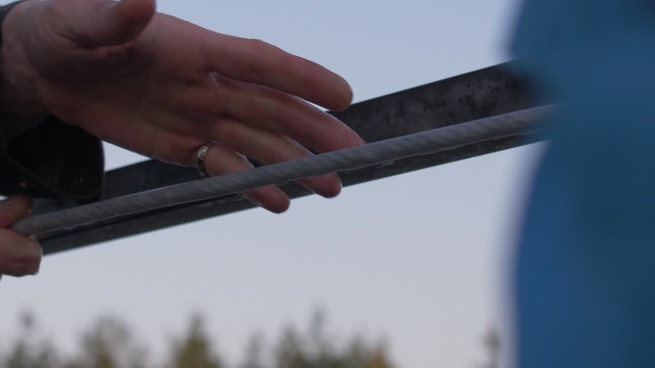 manos tirando de una cuerda con gotas de agua en un ferry de metal
