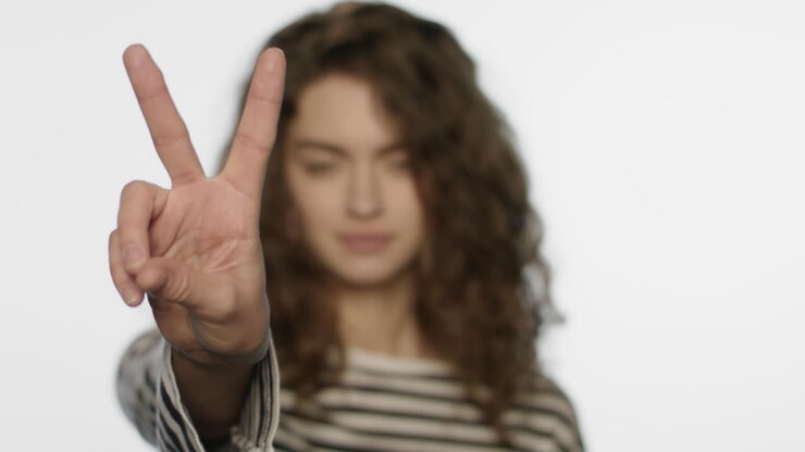 Ragazza allegra che mostra il segno della vittoria con la mano. Ritratto di donna che mostra il gesto della vittoria.