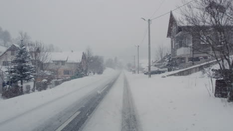 Driving-on-snow-covered-road-through-small-town