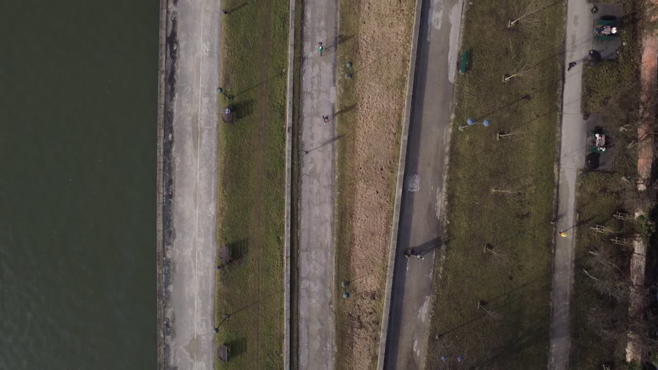 Luftfoto oppefra af folk, der går og cykler på flodbredsstier