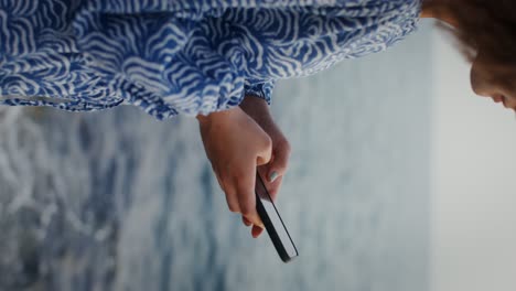 woman using phone by the ocean