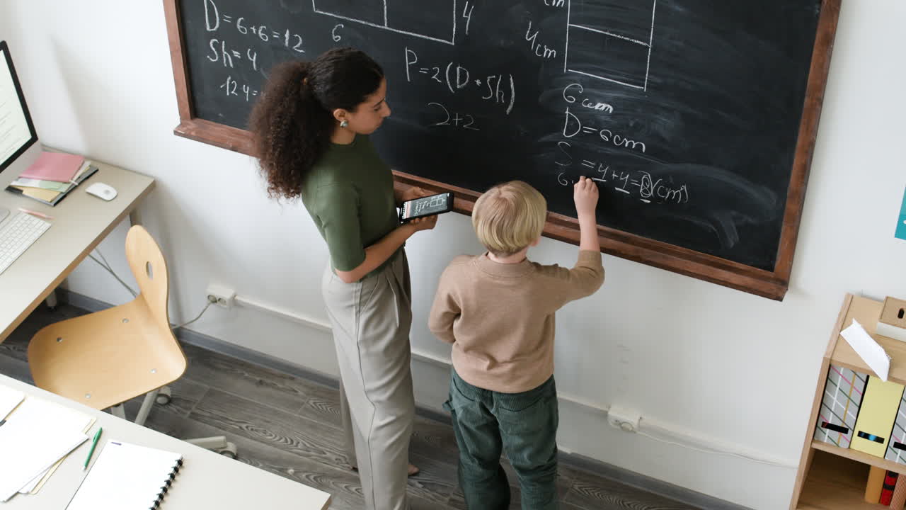 Teacher and Student Working on Math Problems on a Chalkboard